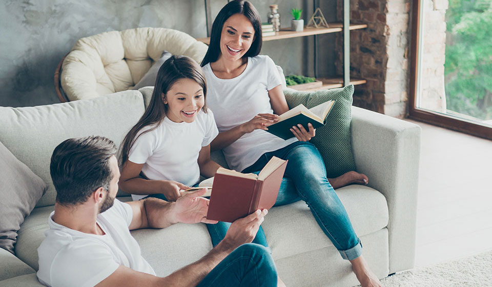 Happy family sitting around sofa reading books