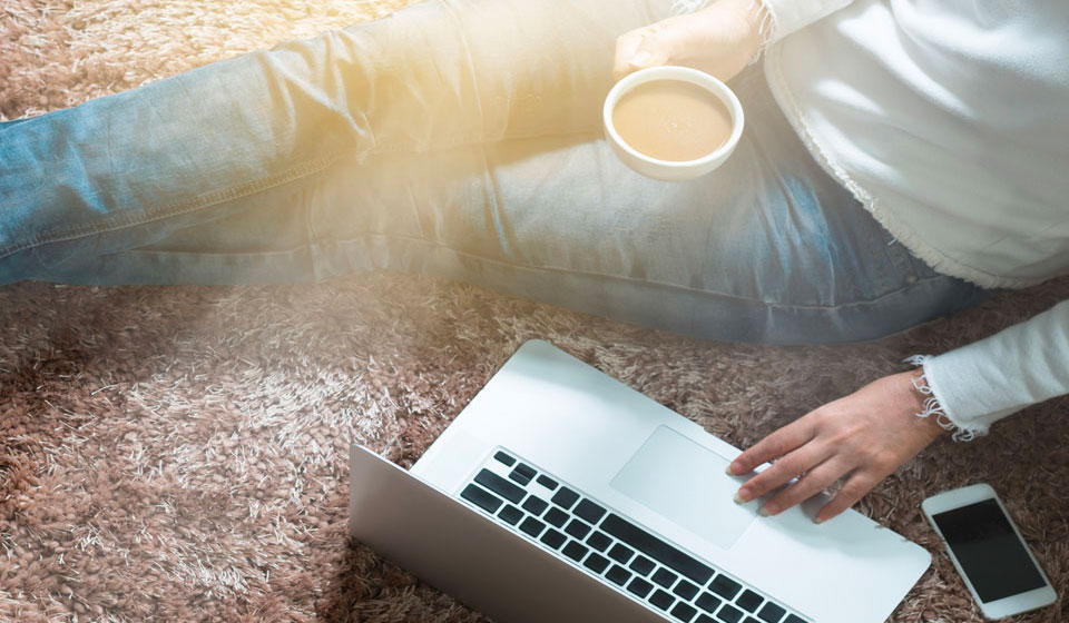 Girl sitting on plush carpet using her laptop