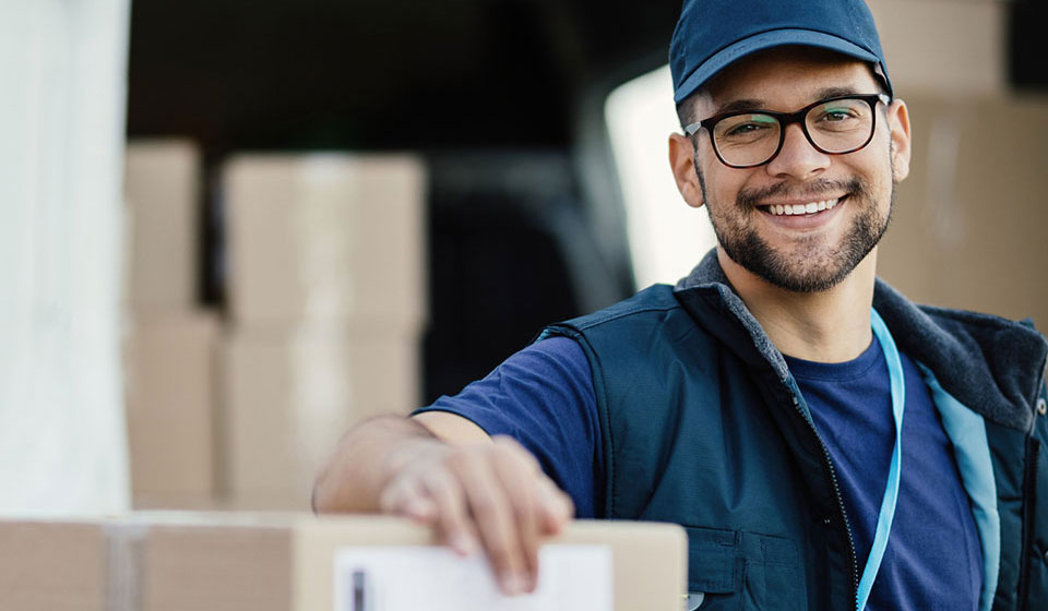 Smiling delivery man resting arm on a parcel