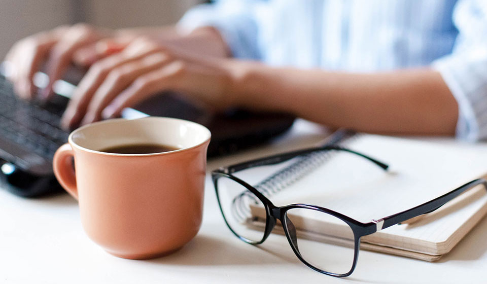 Coffee and glasses resting on a table with a notepad