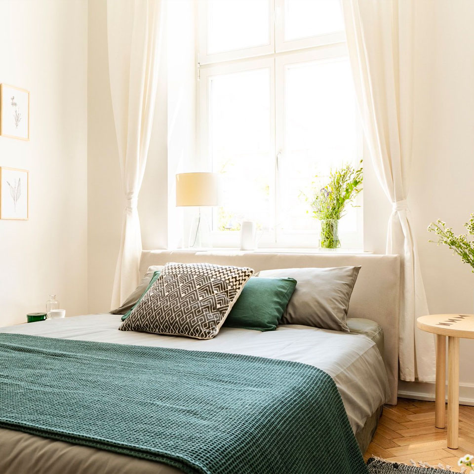Bed with lots of pillows and large window behind it